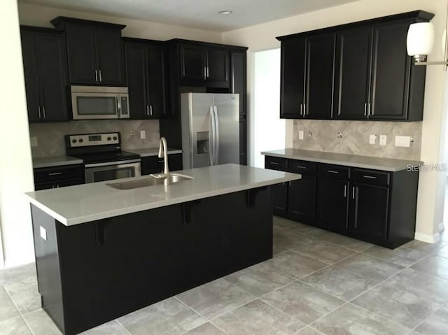 kitchen with sink, a kitchen breakfast bar, stainless steel appliances, and an island with sink