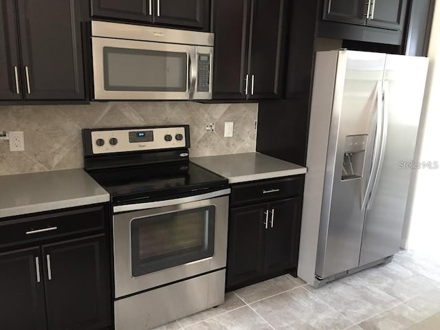 kitchen with stainless steel appliances, light tile patterned floors, and backsplash