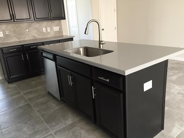 kitchen featuring tile patterned floors, sink, a center island with sink, stainless steel dishwasher, and backsplash