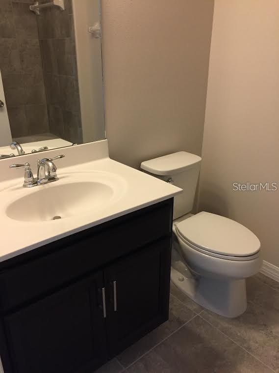 bathroom featuring tile patterned flooring, vanity, and toilet