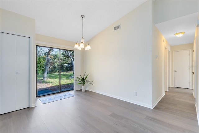 interior space featuring lofted ceiling, a notable chandelier, and light hardwood / wood-style flooring