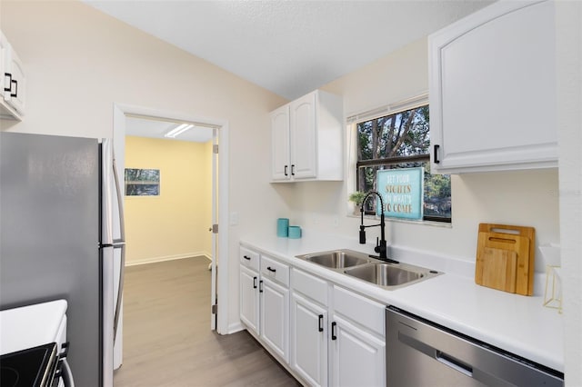 kitchen featuring lofted ceiling, sink, light hardwood / wood-style flooring, stainless steel appliances, and white cabinets