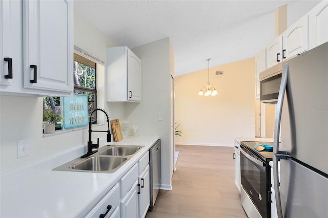 kitchen with sink, white cabinetry, an inviting chandelier, hanging light fixtures, and stainless steel appliances