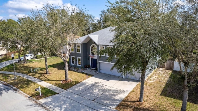 view of front facade with concrete driveway, a front yard, fence, and stucco siding