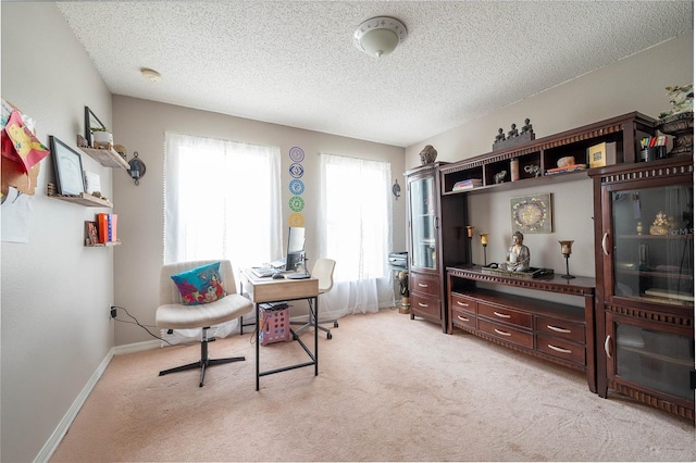 office space with light carpet, a textured ceiling, and baseboards