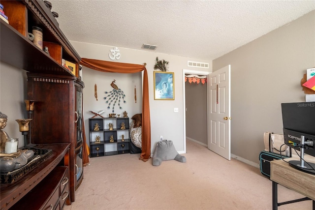 bedroom featuring light carpet, visible vents, and a textured ceiling