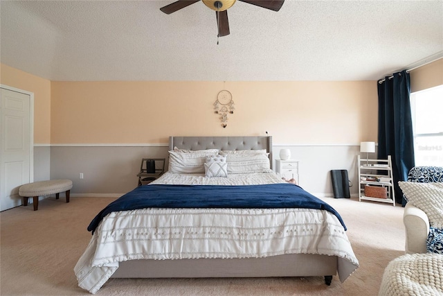 carpeted bedroom featuring a ceiling fan, a textured ceiling, and baseboards