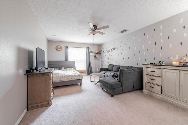 bedroom featuring visible vents, a ceiling fan, light carpet, a textured ceiling, and baseboards