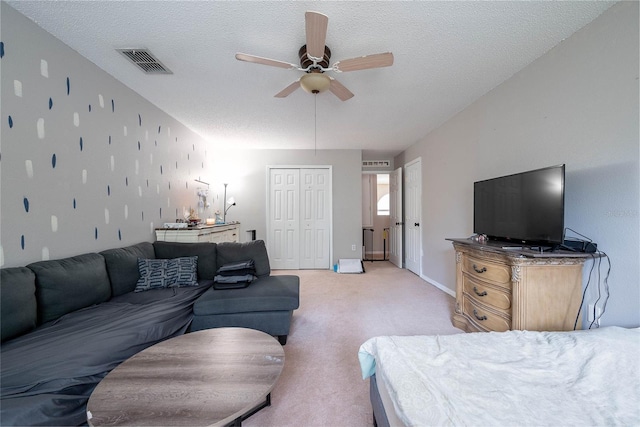 living room with a ceiling fan, visible vents, a textured ceiling, and light colored carpet