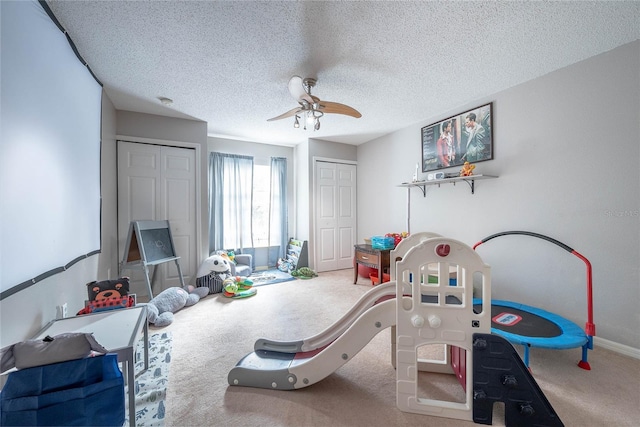 rec room with a textured ceiling, carpet flooring, a ceiling fan, and baseboards