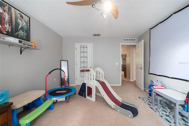 rec room featuring carpet, visible vents, ceiling fan, and a textured ceiling