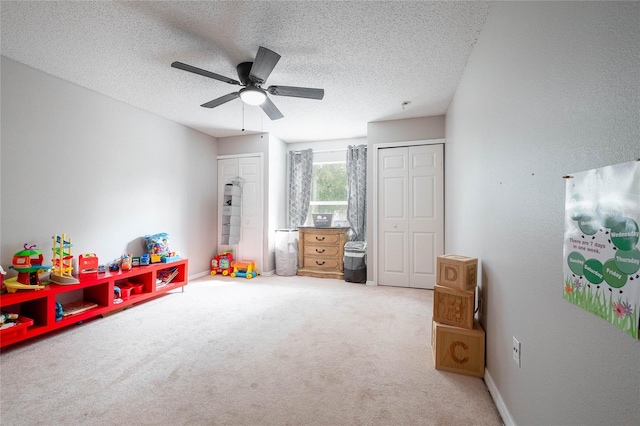 playroom with carpet floors, ceiling fan, baseboards, and a textured ceiling