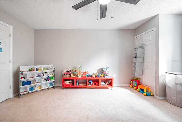 game room featuring a textured ceiling, carpet flooring, a ceiling fan, and baseboards