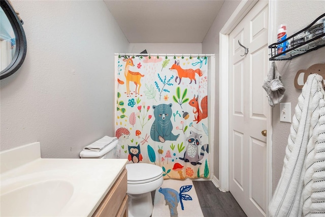 bathroom with a shower with curtain, vanity, toilet, and wood finished floors