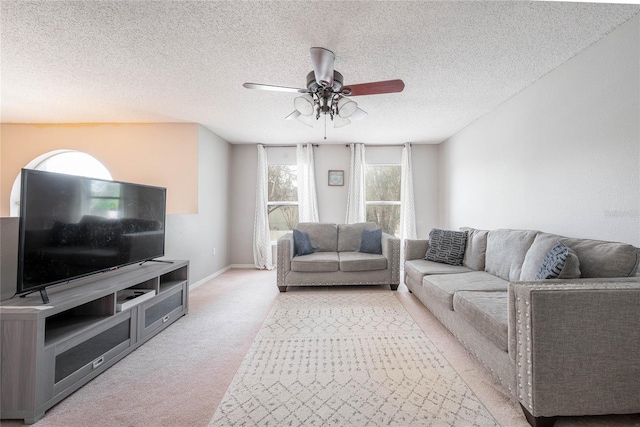 living area featuring light carpet, ceiling fan, and a textured ceiling