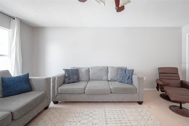 carpeted living room with a ceiling fan, a textured ceiling, and baseboards