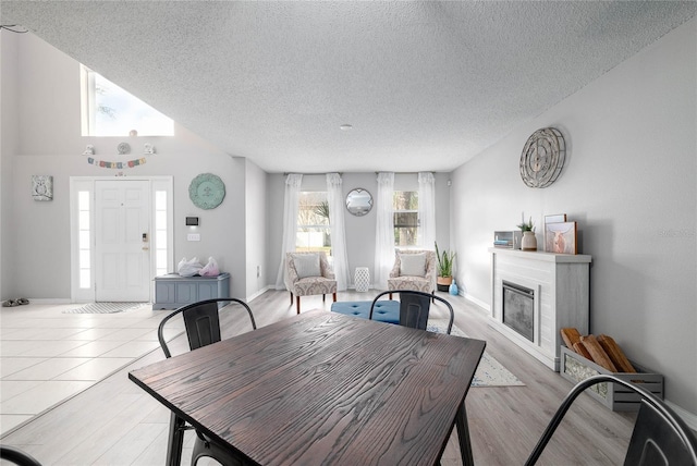 dining room featuring a glass covered fireplace, a textured ceiling, and wood finished floors