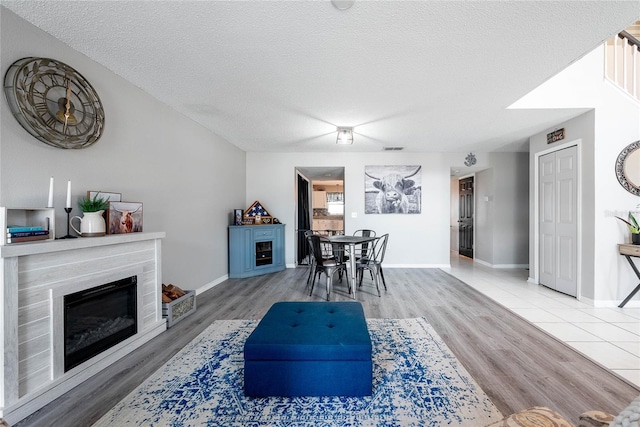 dining room featuring baseboards, wood finished floors, a textured ceiling, and a high end fireplace