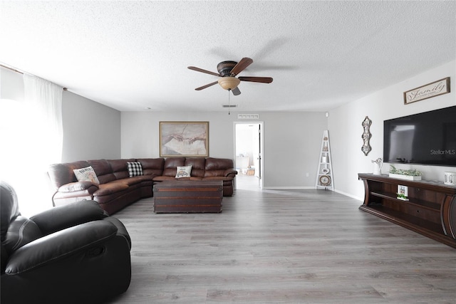 living room featuring ceiling fan, a textured ceiling, visible vents, and wood finished floors