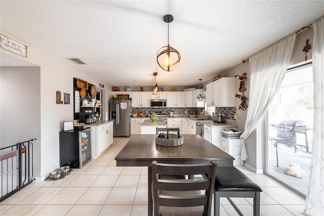 dining area with light tile patterned floors, visible vents, and a textured ceiling