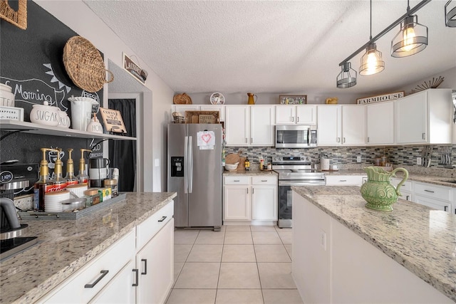 kitchen featuring light tile patterned floors, tasteful backsplash, appliances with stainless steel finishes, white cabinetry, and pendant lighting