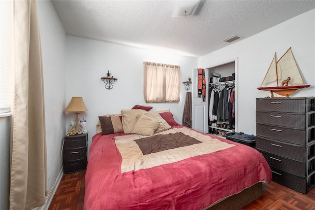 bedroom with a closet, dark parquet floors, and a textured ceiling