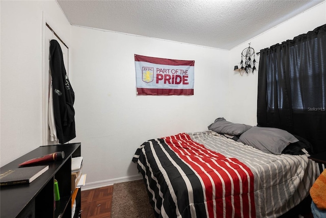 bedroom featuring dark parquet floors and a textured ceiling