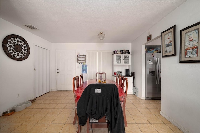 dining area featuring a textured ceiling and light tile patterned floors