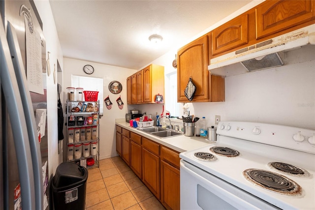 kitchen with stainless steel refrigerator, sink, light tile patterned floors, and white range with electric stovetop