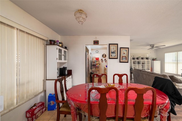 tiled dining area with a textured ceiling and ceiling fan