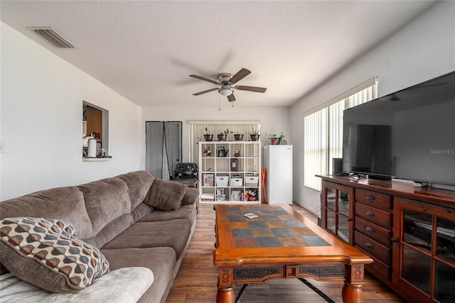 living room with hardwood / wood-style flooring, ceiling fan, and a textured ceiling