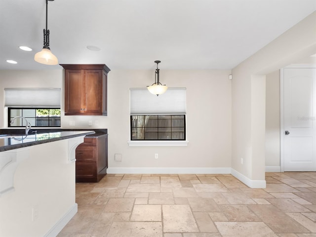 kitchen with pendant lighting, sink, and dark stone counters