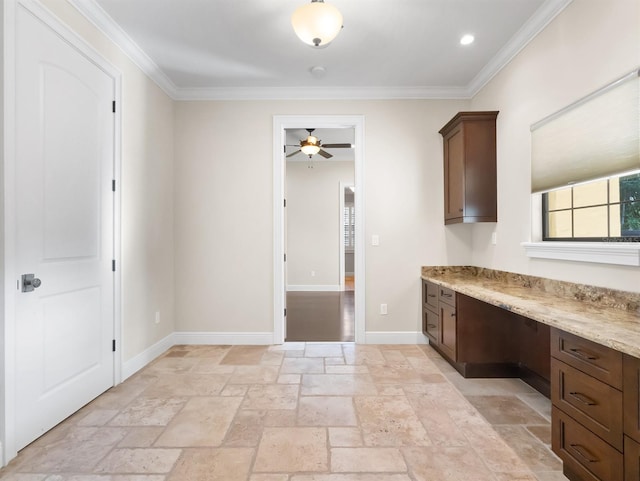 kitchen featuring light stone counters, built in desk, ornamental molding, and ceiling fan