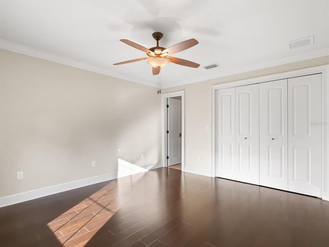 unfurnished bedroom with a closet, crown molding, dark hardwood / wood-style floors, and ceiling fan