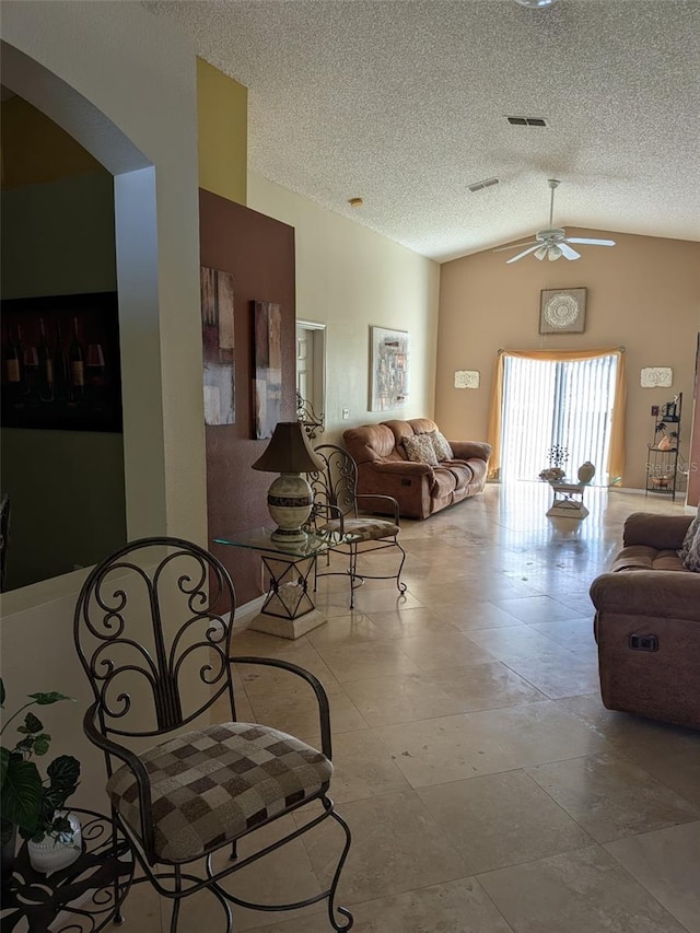 living room with ceiling fan, lofted ceiling, and a textured ceiling