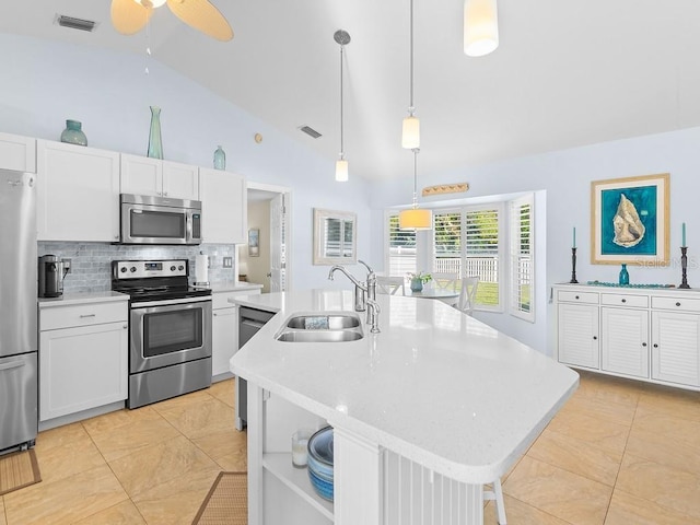 kitchen with sink, appliances with stainless steel finishes, white cabinetry, hanging light fixtures, and an island with sink