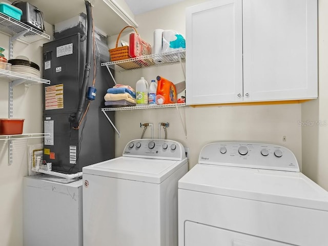 laundry room featuring cabinets, heating unit, and washer and clothes dryer