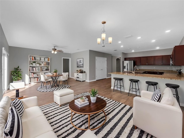 living room featuring ceiling fan with notable chandelier, dark hardwood / wood-style floors, and sink