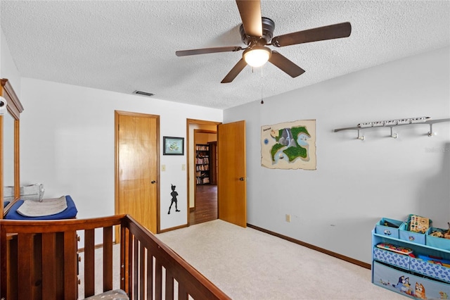 bedroom with ceiling fan, light colored carpet, and a textured ceiling