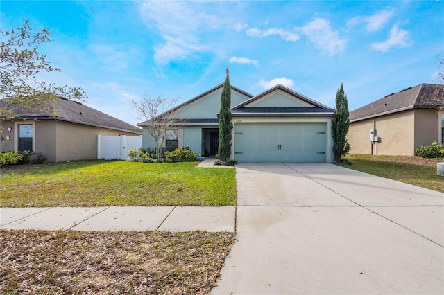 view of front of house featuring driveway, an attached garage, fence, a front lawn, and stucco siding