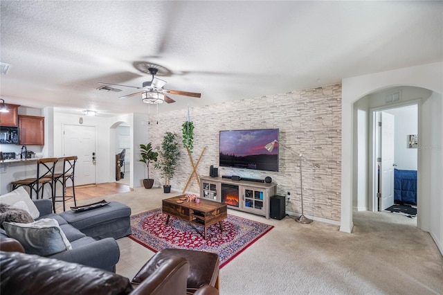 living area featuring arched walkways, visible vents, and a textured ceiling