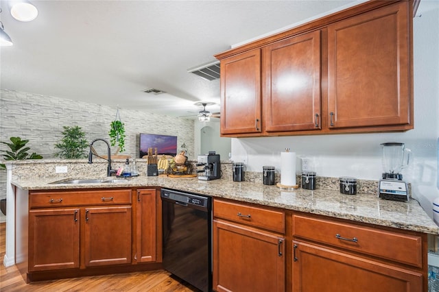 kitchen featuring light stone counters, a peninsula, a sink, visible vents, and black dishwasher