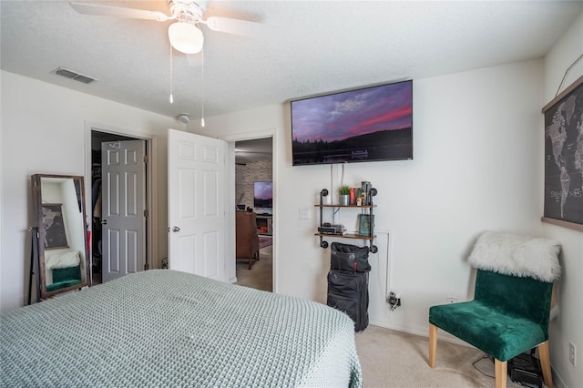 bedroom featuring carpet floors, a textured ceiling, visible vents, and a ceiling fan