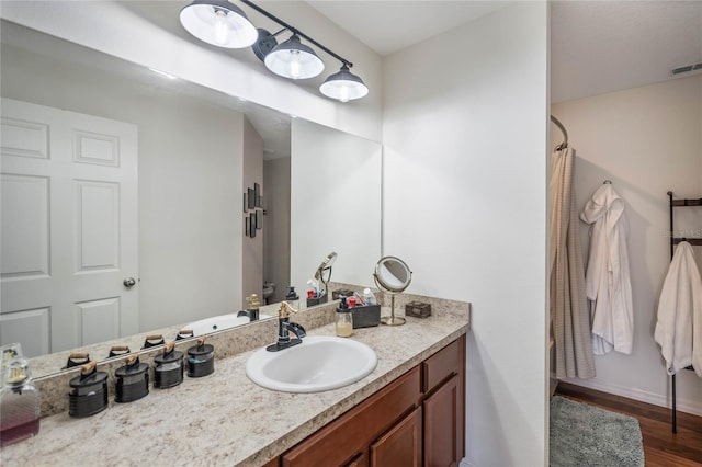 bathroom with baseboards, visible vents, a shower with curtain, wood finished floors, and vanity