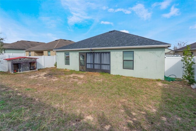 back of property with stucco siding, a fenced backyard, a lawn, and roof with shingles