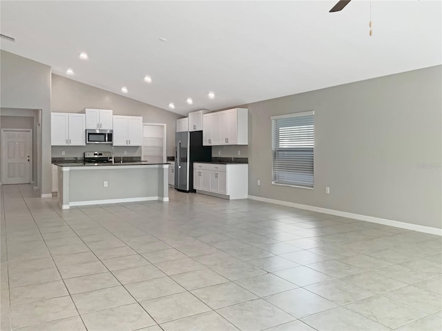 kitchen featuring high vaulted ceiling, a center island with sink, ceiling fan, stainless steel appliances, and white cabinets