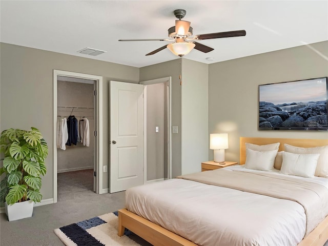 carpeted bedroom with a walk in closet, ceiling fan, and a closet