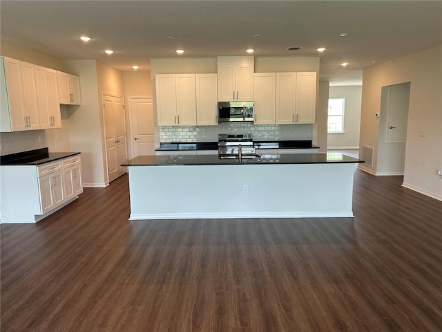 kitchen with white cabinetry, stainless steel appliances, and dark countertops