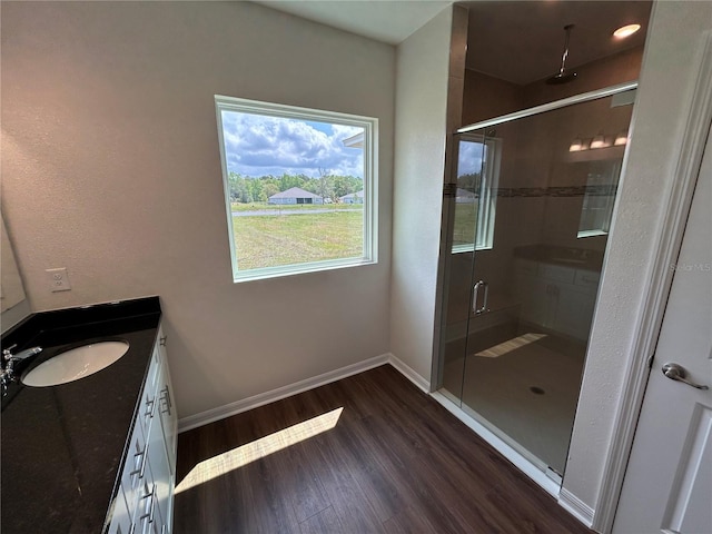 full bathroom with a shower stall, baseboards, wood finished floors, and vanity