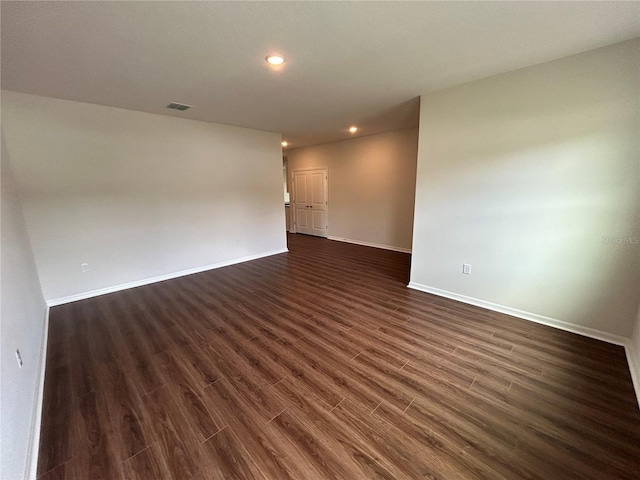 unfurnished room with baseboards, dark wood-style floors, visible vents, and recessed lighting